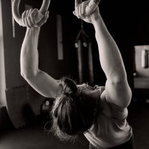 Grayscale Photo of a Person Holding Gymnastic Rings